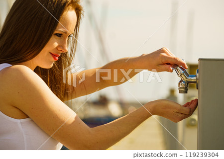 Woman drinking water from tap in marina. 119239304