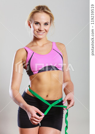 Fit woman measuring her belly with measure tape Fit woman measuring her belly with measure tape 119239519