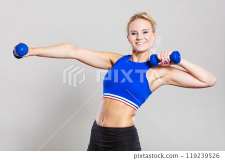 Fit woman lifting dumbbells weights 119239526