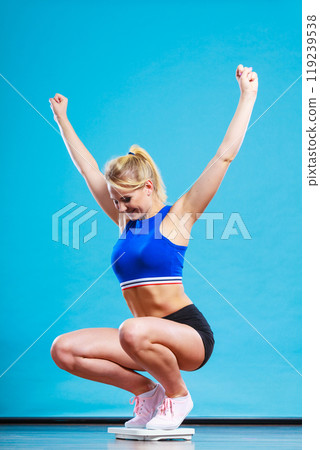 Joyful girl standing on weighing scale 119239538