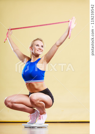Joyful girl standing on bathroom scales Joyful girl standing on bathroom scales 119239542