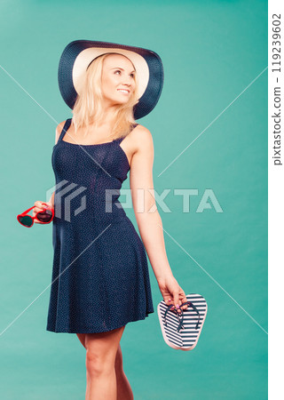 Woman wearing short dress holding flip flops and sunglasses Woman wearing short dress holding flip flops and sunglasses 119239602