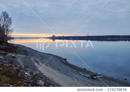 Sunset with dark blue clouds and streak of bright orange golden sunlight. Novosibirsk, Ob river bank Sunset with dark blue clouds and streak of bright orange golden sunlight. Novosibirsk, Ob river bank 119239636