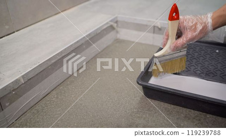 Construction worker picking up waterproofing material with brush. Construction worker picking up waterproofing material with brush. 119239788