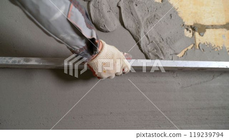 Construction worker leveling concrete mortar using aluminum straight edge Construction worker leveling concrete mortar using aluminum straight edge 119239794
