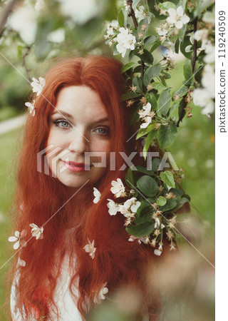Redhead young woman with green eyes and freckles in white apple blossom, retro photo 119240509