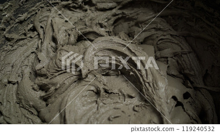 Construction worker mixing tile adhesive or cement in a bucket. 119240532