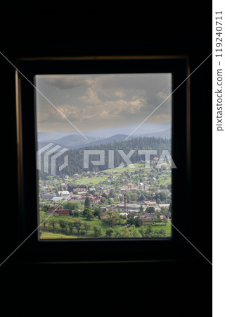 Vorokhta village view through window frame showcasing Carpathian mountains and green hills 119240711