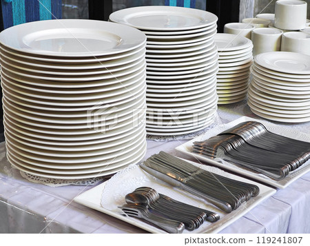White plates and cutlery stacked on the table. White plates and cutlery stacked on the table. 119241807
