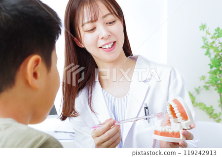 A female doctor instructing a boy on brushing his teeth A female doctor instructing a boy on brushing his teeth 119242913