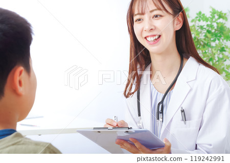 A young woman in a white coat examining a child A young woman in a white coat examining a child 119242991