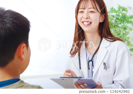 A young woman in a white coat examining a child A young woman in a white coat examining a child 119242992