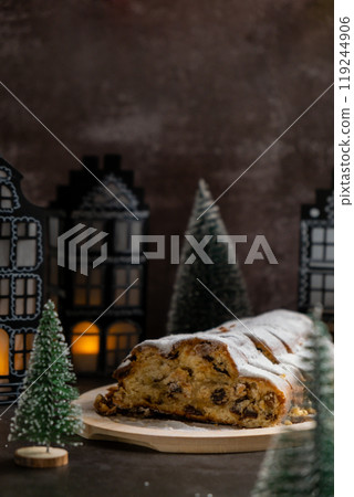 Christmas Stollen in Christmas lights and decoration. Traditional sweet fruit loaf with icing sugar festive pastry dessert. Holiday baking food 119244906