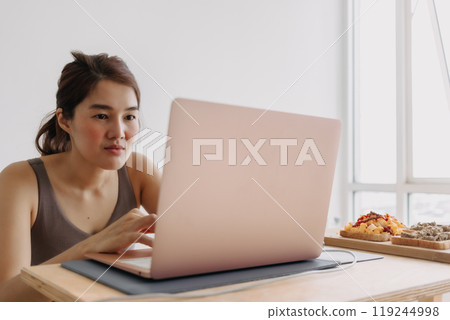 Woman is working at home with cozy clothes and breakfast meal. Woman is working at home with cozy clothes and breakfast meal. 119244998
