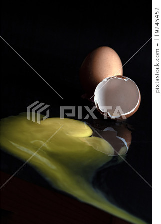 View of Broken egg yolk with Broken raw chicken eggshell in front of Fresh chicken egg (Hen eggs) on Dark background. 119245452