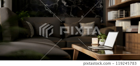 A side view of a laptop on a coffee table in a modern black living room. 119245783