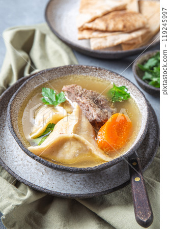 Traditional Jewish Kreplach soup with meat and carrot, gray background 119245997