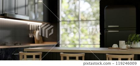 A wooden kitchen island or dining table in a sleek black kitchen with modern appliances. 119246009