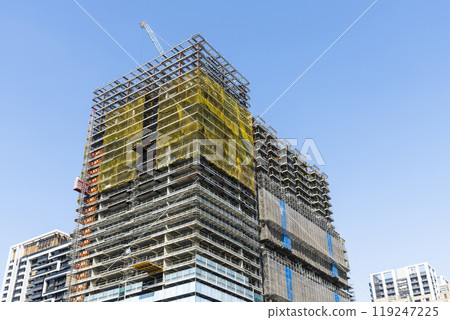 Low-angle view of steel structures of building construction with a blue sky background. Low-angle view of steel structures of building construction with a blue sky background. 119247225