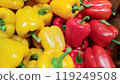 Brightly colored red and yellow peppers lined up at a fruit and vegetable store_1709 119249508