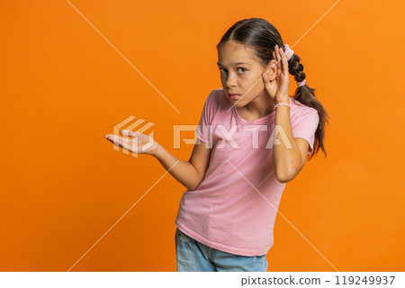 Child girl kid trying hear you looking confused and frowning, keeping arm near ear for louder voice 119249937