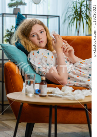 Sick ill woman suffering from cold or allergy lying on home sofa sneezes wipes snot into napkin Sick ill woman suffering from cold or allergy lying on home sofa sneezes wipes snot into napkin 119250023
