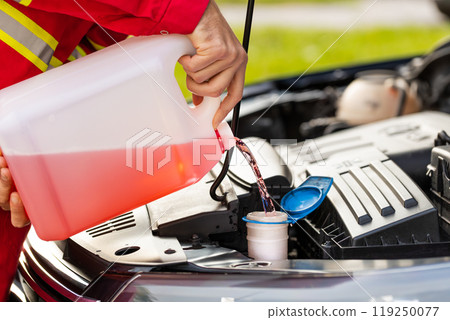 Service worker man pours car fluid windscreen red cleaning washer glass summer or winter cleaner 119250077