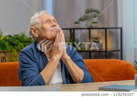 Worried senior elderly man praying sincerely with folded arms asking God for help, begging apology Worried senior elderly man praying sincerely with folded arms asking God for help, begging apology 119250107