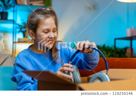 Happy child girl shopper unpacking cardboard box delivery parcel online shopping purchase at home Happy child girl shopper unpacking cardboard box delivery parcel online shopping purchase at home 119250146