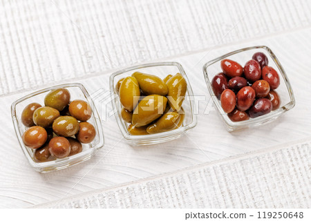 An assortment of various olives presented in a bowl, showcasing different colors, textures, and flavors An assortment of various olives presented in a bowl, showcasing different colors, textures, and flavors 119250648