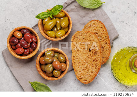 An assortment of various olives presented in a bowl, showcasing different colors, textures, and flavors 119250654