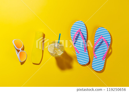 A vibrant summer vacation scene with flip flops, shades, and cocktail 119250656