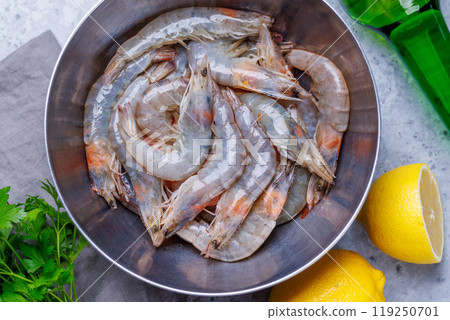 Fresh raw shrimps, accompanied by sprigs of fresh parsley and juicy lemon 119250701