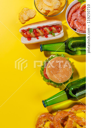 A vibrant photo showcasing beer surrounded by various snacks and fast food 119250710