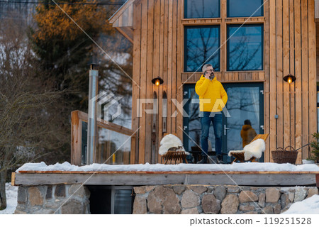 Man working from cozy cabin in mountains, making call with client. Concept of remote work from beautiful, peaceful location. Hygge at work. 119251528
