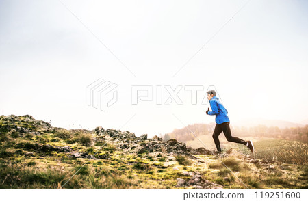 Male runner jogging in nature on dirt running trail. Morning running training for young man. 119251600