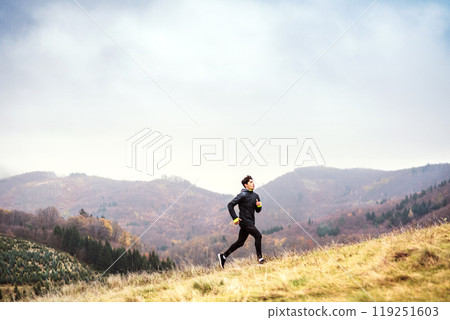 Male runner jogging in nature on dirt running trail. Morning running training for young man. 119251603