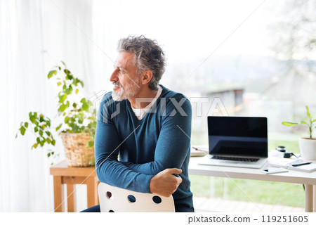 Homeoffice for handsome man. Man sitting on chair backward, looking out of window. Telecommuting. 119251605