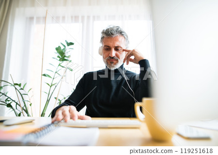 Homeoffice for handsome man. Man listening music while working in his office at home. Telecommuting. Homeoffice for handsome man. Man listening music while working in his office at home. Telecommuting. 119251618