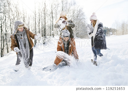 Friends in snowball fight in snowy nature, throwing snow and having fun. First snowfall of the season. 119251653