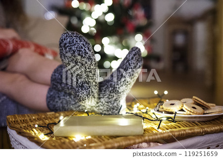 Close up of thick knitted socks on feet. Comfort and hygge atmosphere during Christmas at home. 119251659