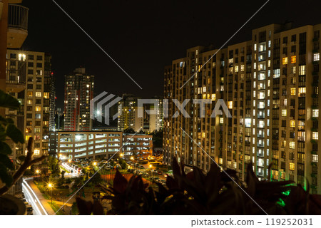 Night city. Multistorey residential building. The windows of the house glow in the dark. 119252031