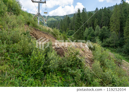 Landslide of soil due to felling of trees in the forest. Carpathians, cable car in nature. 119252034