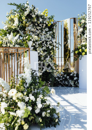 A wedding arch, decorated with flowers, stands on a podium, stands in the open air 119252767