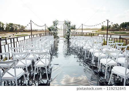 A wedding arch, decorated with flowers, stands on a podium, stands in the open air 119252845