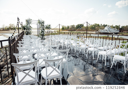 A wedding arch, decorated with flowers, stands on a podium, stands in the open air 119252846