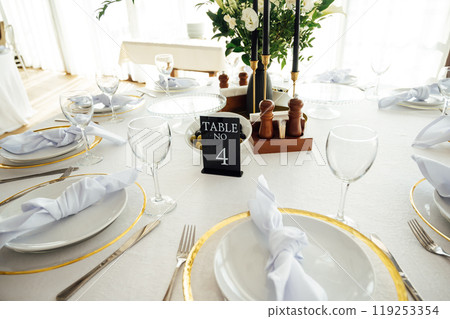 Luxurious restaurant. Luxurious interior, white tables, serving dishes and glasses for guests Luxurious restaurant. Luxurious interior, white tables, serving dishes and glasses for guests 119253354