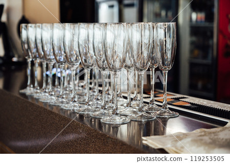 A lot of empty wine glasses. Row of clean glass transparent glasses are on a table on banquet in a bar A lot of empty wine glasses. Row of clean glass transparent glasses are on a table on banquet in a bar 119253505