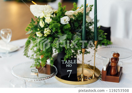 Luxurious restaurant. Luxurious interior, white tables, serving dishes and glasses for guests. Green decor 119253508