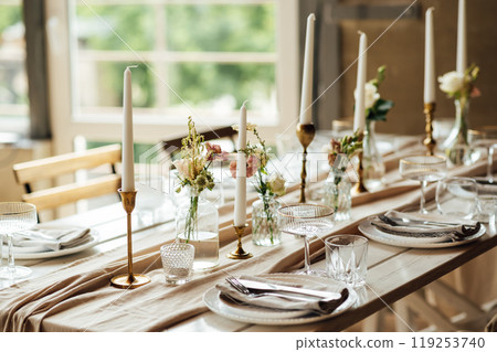 Elegant neutral coloured wedding table scape with flowers and candles 119253740